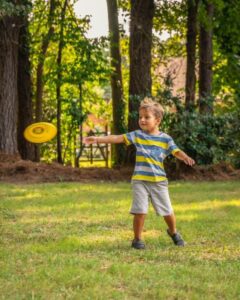 A little boy playing frisbee in his backyard